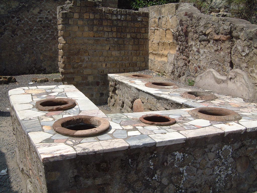 II.7/6 Herculaneum, May 2001. Looking south across counter in bar room with 7 inset dolia. Photo courtesy of Current Archaeology.